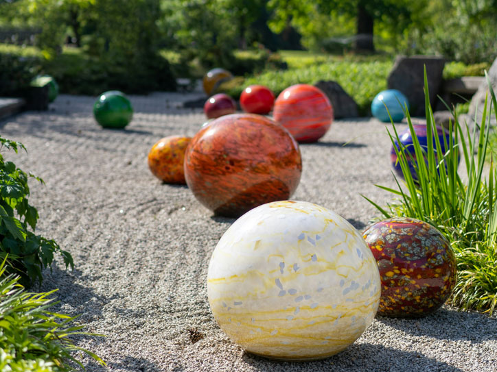 Gartengestaltung mit Kiesweg und dekorativen Gartenkugeln